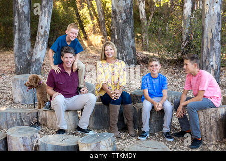 Familie von fünf Sitzen auf Baumstümpfen für einen lässigen Portrait Stockfoto