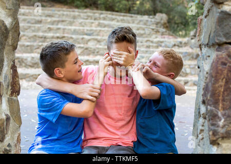 Zwei jüngere Brüder gang Auf älteren Bruder spielerisch Stockfoto