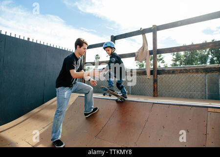 Die jungen Skater Boy über in der Halfpipe mit Instruktor drop bereit Stockfoto