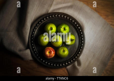 Ansicht von oben von Äpfeln in der Platte über Textilwaren über Tabelle Stockfoto