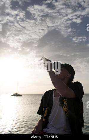 Junger Mann Bier trinken auf See Stockfoto
