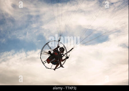Low Angle Menschenbild paragliding gegen bewölkter Himmel Stockfoto
