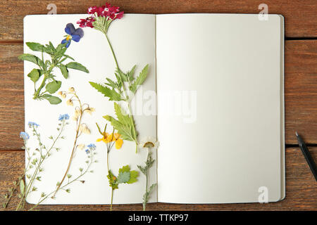 Schöne getrocknete Blumen in Notebook auf hölzernen Hintergrund Stockfoto