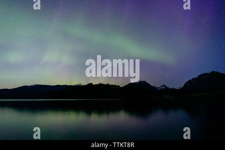 Malerischer Blick auf Northern lights in ruhigen See bei Nacht reflektieren Stockfoto