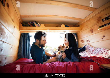 Paar mit Hund beim Entspannen auf Bett im Wohnmobil Stockfoto