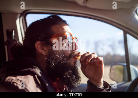 Seitenansicht der männlichen hipster Rauchen elektronische Zigarette im Auto. Stockfoto