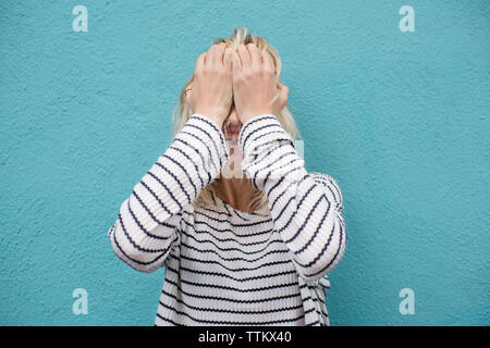 Deprimiert junge Frau das Gesicht weiß Schreien gegen blaue Wand Stockfoto