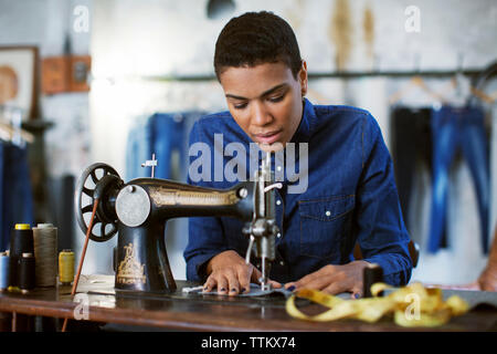 Weibliche Mode Designer mit Nähmaschine in Werkstatt Stockfoto
