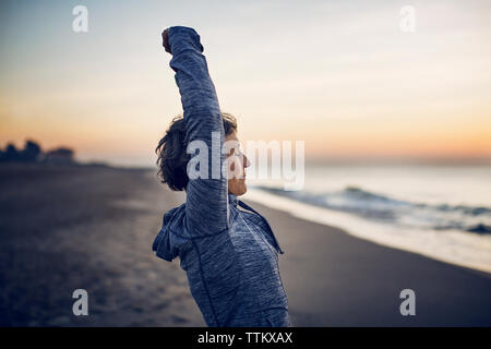 Seitenansicht von der Frau, die sich am Strand gegen Sky Stockfoto