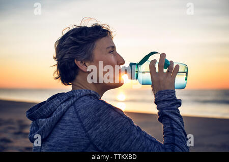 In der Nähe von Frau trinkt Wasser am Strand gegen Sky Stockfoto