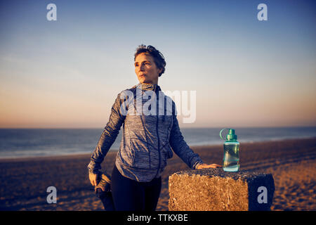 Frau stretching am Strand gegen den klaren Himmel Stockfoto