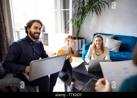 Happy business Leute, die auf der Suche nach Kollegen während der Tagung in kreative Büro Stockfoto