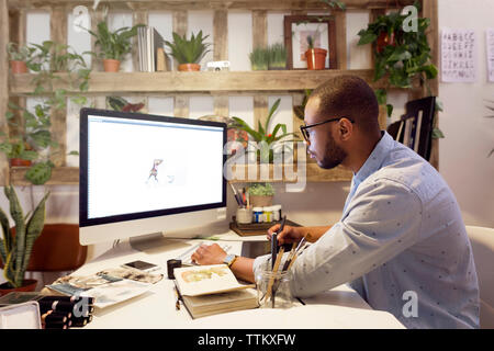 Seitenansicht der männlichen Illustrator, Malerei auf dem Computer in der kreativen Büro Stockfoto