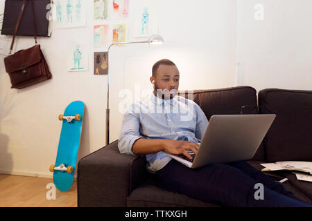 Illustrator mit Laptop beim Sitzen auf einem Sofa in der kreativen Büro Stockfoto