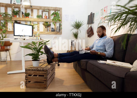 Männliche illustrator mit Laptop beim Sitzen auf einem Sofa in der kreativen Büro Stockfoto