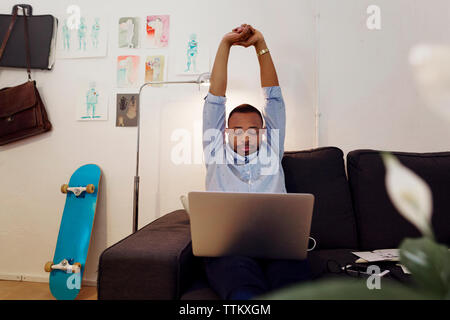 Müde Geschäftsmann stretching Hände während der Arbeit am Laptop in kreative Büro Stockfoto