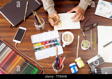 Zugeschnittenes Bild der männlichen Illustrator die Malerei am Schreibtisch in der kreativen Büro Stockfoto