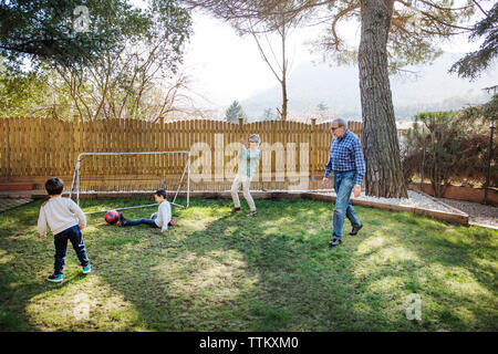 Fröhliche Großeltern mit Enkeln Fußball spielen im Hof Stockfoto