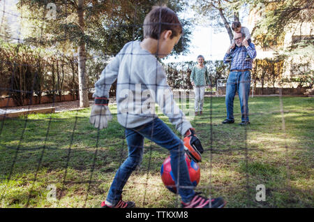 Junge spielt Fußball mit Familie im Hof Stockfoto