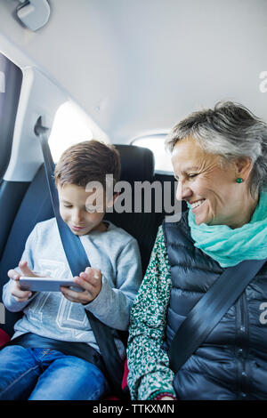 Gerne ältere Frau an Enkel mittels Smart Phone in Auto suchen Stockfoto
