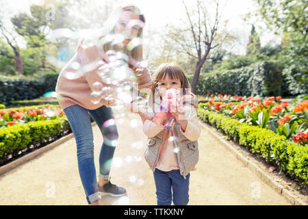 Mutter und Tochter spielen mit Bubble Gun im Park Stockfoto