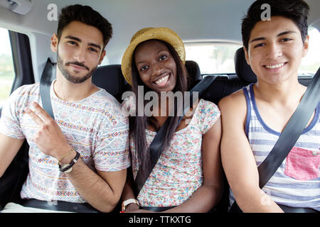 Portrait von glücklichen Frau sitzt mit männlichen Freunden im Auto. Stockfoto