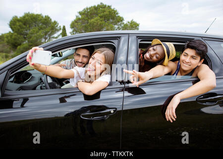Freundliche männliche und weibliche Freunde unter selfie während im Auto sitzen Stockfoto