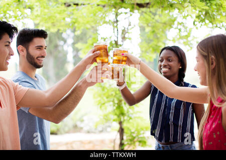 Glücklich, multi-ethnischen Freunde toasten Eistee Gläser im Hof Stockfoto