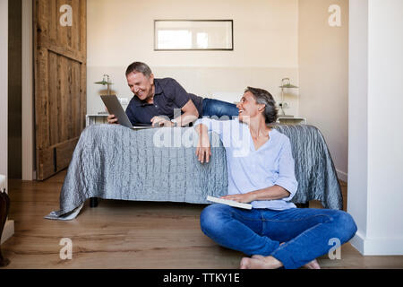 Glückliche Frau an der älteren Mann mit Laptop im Schlafzimmer suchen Stockfoto