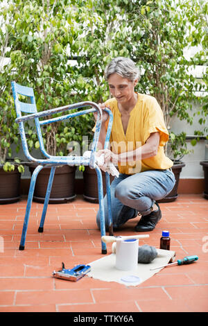 Die ganze Länge der reifen Frau Malerei Stuhl bei Hof Stockfoto