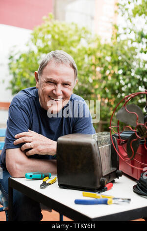 Portrait von Happy älterer Mann Instandsetzung Vintage Radio im Hof Stockfoto