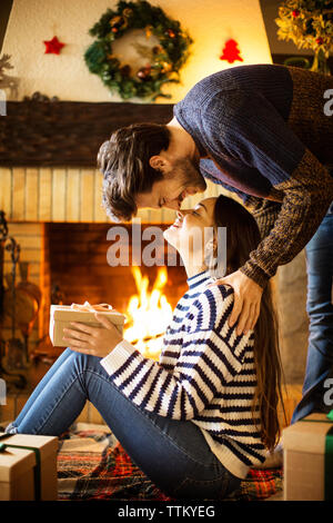 Romantisches Paar mit weihnachtsgeschenk, das zu Hause Nasen reibt Stockfoto