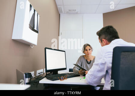 Der Arzt im Gespräch mit Frau schließen, während Sitzen im Krankenhaus Stockfoto