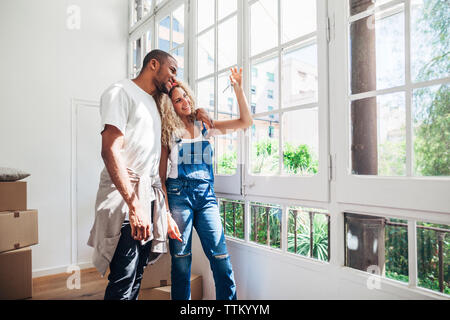 Lächelnd Pärchen auf der Suche nach Schlüssel, während man durch die Fenster zu Hause Stockfoto