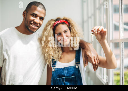 Porträt der Mann mit der Frau auf der Suche nach Schlüssel, während man durch die Fenster im Haus Stockfoto