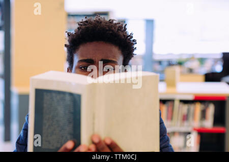 Mann lesen Buch während der Sitzung in Bibliothek Stockfoto