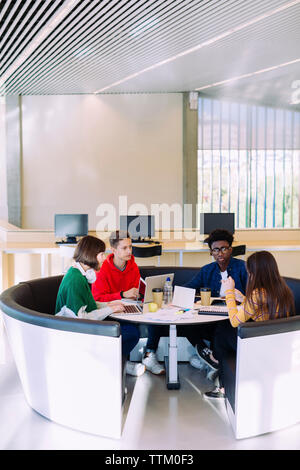 Freunde diskutieren während ihres Studiums in Bibliothek Stockfoto