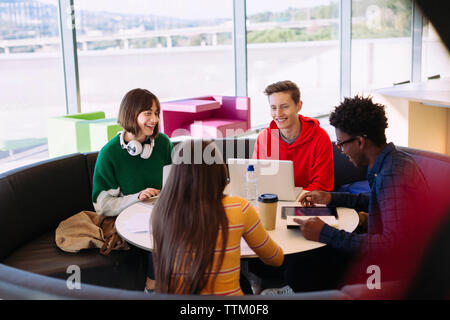 Lächelnd Freunde diskutieren während der Sitzung durch die Fenster in der Bibliothek Stockfoto