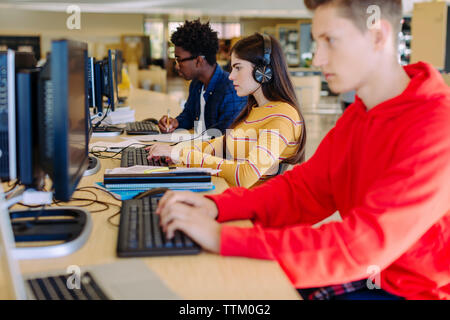 Freunde mithilfe von Desktop Computern während der Sitzung in Bibliothek Stockfoto