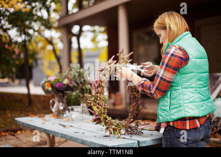 Frau, die Blumenkranz auf Tisch Stockfoto