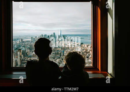 Ansicht der Rückseite des Brüder im Stadtbild durch das Fenster zu hause suchen Stockfoto