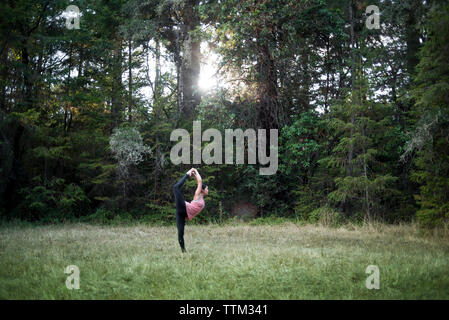 Volle Länge des Frau üben Natarajasana gegen Bäume im Feld Stockfoto