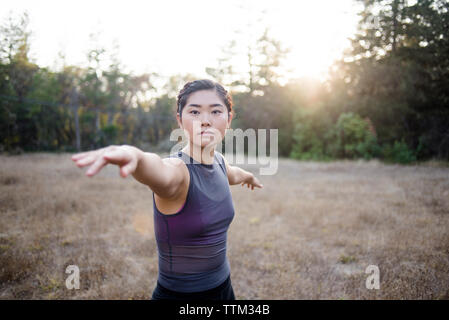 Portrait von selbstbewusste Frau mit ausgestreckten Armen Yoga in das Feld Stockfoto