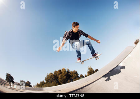 Low Angle Sicht des Menschen Durchführung Stunt in Skateboard Park gegen blauen Himmel Stockfoto