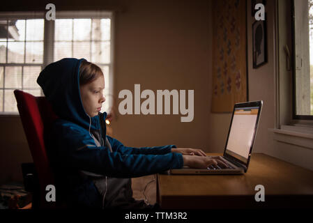 Seitenansicht der Boy mit Laptop, während zu Hause sitzen Stockfoto