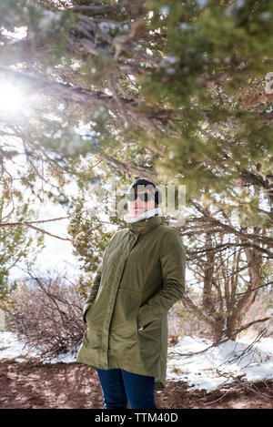 Frau mit Händen in den Taschen der Winter steht die Zweige an der Wüste im Winter Stockfoto