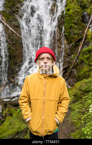 Porträt der jungen mit Händen in den Taschen gegen Wasserfall im Olympic National Park Stockfoto