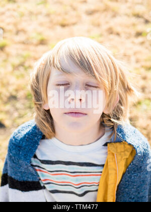 Hohe Betrachtungswinkel und der netten Jungen mit geschlossenen Augen stehen auf Feld Stockfoto