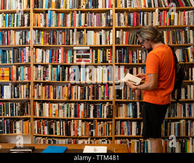 Mann lesen Buch in St Georges secondhand Buchladen im Prenzlauer Berg, Berlin, Deutschland Stockfoto