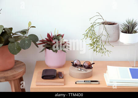 Hohe Betrachtungswinkel von persönlichen Accessoires mit Pflanzen und Bücher auf hölzernen Tisch gegen die Wand zu Hause angeordnet Stockfoto